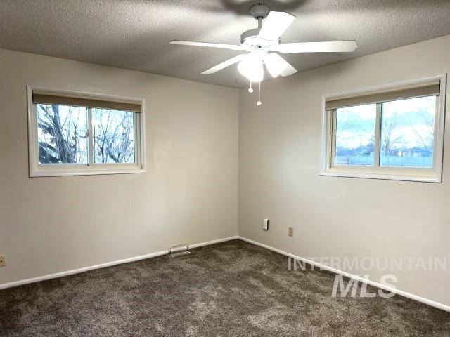 995 E 15th N, Mountain Home, ID 83647 - empty room featuring plenty of natural light, a ceiling fan, dark carpet, and a textured ceiling