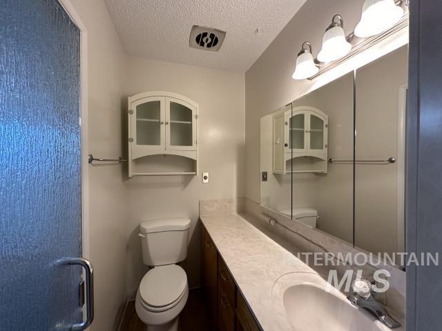 995 E 15th N, Mountain Home, ID 83647 - full bathroom featuring toilet, a textured ceiling, and vanity