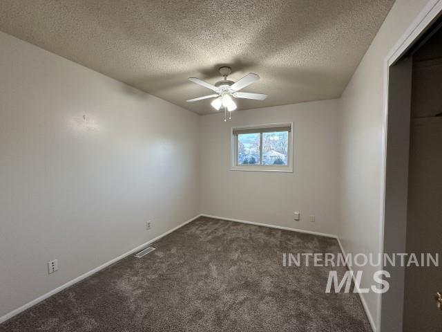995 E 15th N, Mountain Home, ID 83647 - empty room featuring ceiling fan, a textured ceiling, dark colored carpet, baseboards, and visible vents