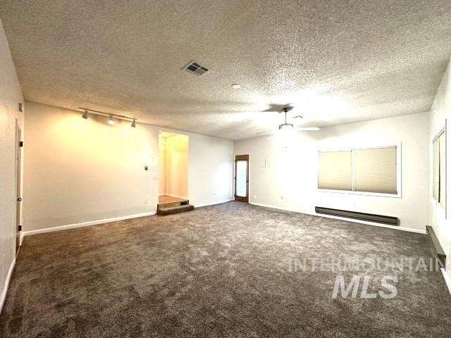 995 E 15th N, Mountain Home, ID 83647 - carpeted empty room featuring ceiling fan, visible vents, baseboard heating, rail lighting, and baseboards