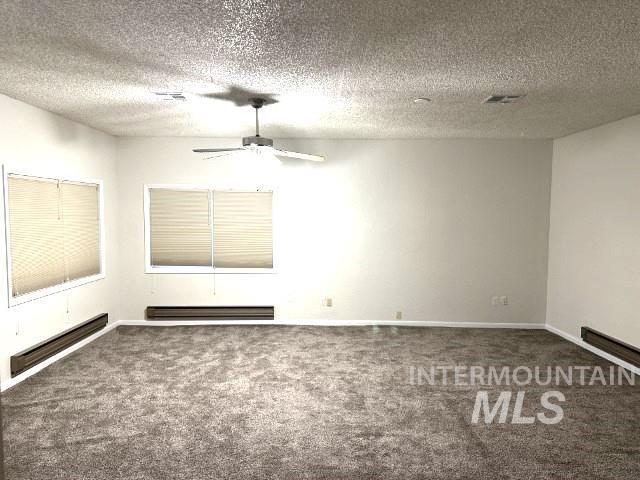 995 E 15th N, Mountain Home, ID 83647 - carpeted empty room featuring ceiling fan, baseboard heating, a baseboard heating unit, and a textured ceiling