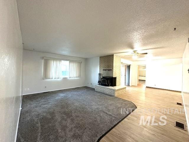 995 E 15th N, Mountain Home, ID 83647 - unfurnished living room featuring a textured ceiling, a ceiling fan, baseboards, wood finished floors, and visible vents