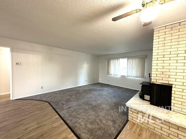 995 E 15th N, Mountain Home, ID 83647 - unfurnished living room with baseboards, a wood stove, a ceiling fan, and a textured ceiling