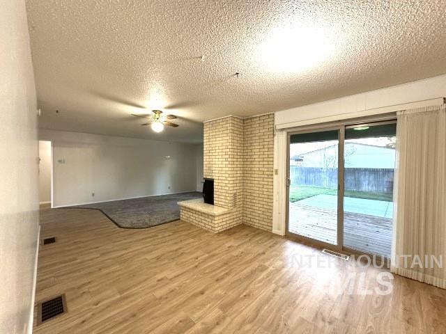 995 E 15th N, Mountain Home, ID 83647 - unfurnished living room with visible vents, a ceiling fan, a textured ceiling, and wood finished floors