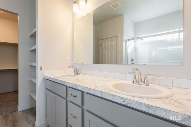 bathroom with walk in shower, vanity, and hardwood / wood-style floors