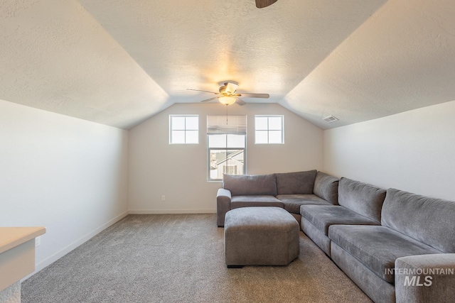 living room with ceiling fan, lofted ceiling, light carpet, and a textured ceiling