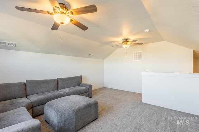 carpeted living room featuring ceiling fan, vaulted ceiling, and a textured ceiling