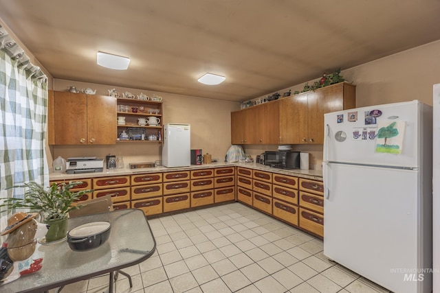 702 N D St, Grangeville, ID 83530 - kitchen featuring freestanding refrigerator, brown cabinetry, open shelves, light tile patterned floors, and light countertops