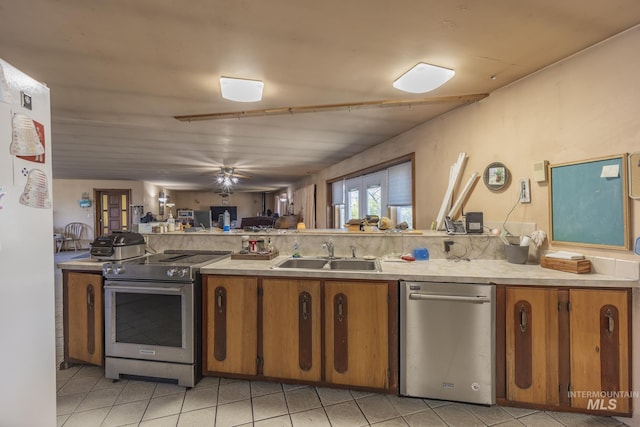 702 N D St, Grangeville, ID 83530 - kitchen featuring a sink, appliances with stainless steel finishes, brown cabinetry, and light tile patterned flooring