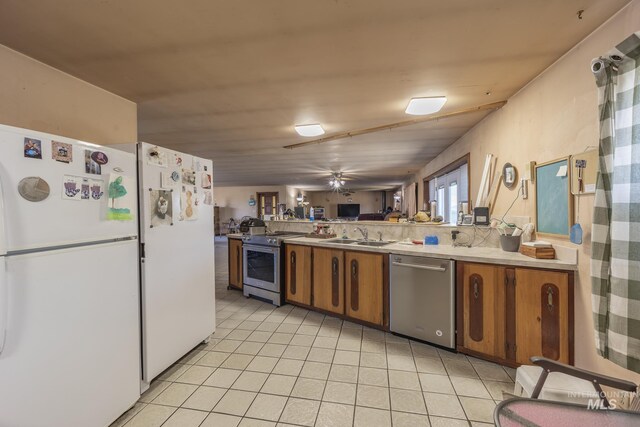 702 N D St, Grangeville, ID 83530 - kitchen with appliances with stainless steel finishes, brown cabinetry, light countertops, light tile patterned floors, and a ceiling fan