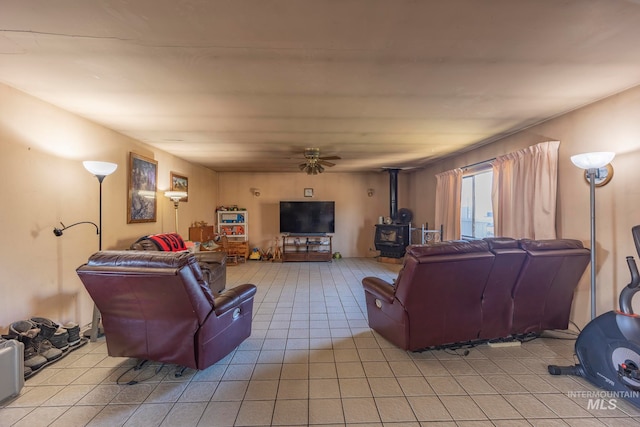 living room with ceiling fan, light tile patterned flooring, and a wood stove