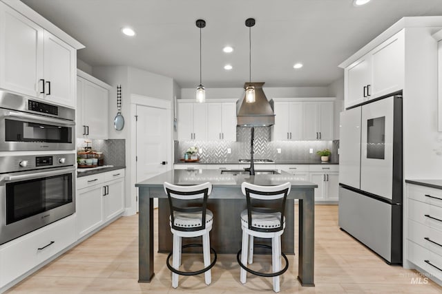 kitchen featuring double oven, refrigerator with glass door, backsplash, light wood-type flooring, and white cabinetry