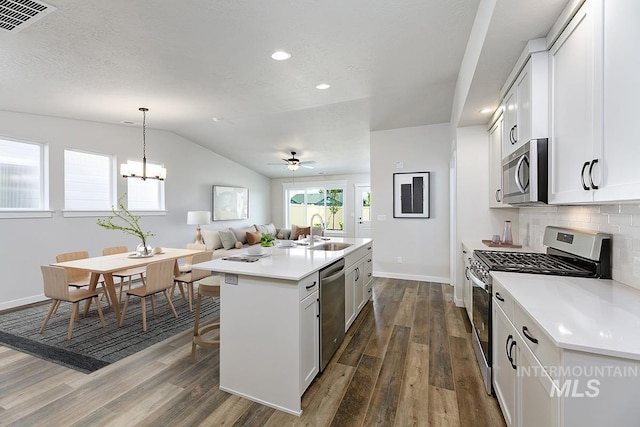 kitchen with dark wood-type flooring, white cabinets, sink, an island with sink, and stainless steel appliances