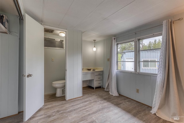 unfurnished bedroom with ensuite bathroom and light wood finished floors