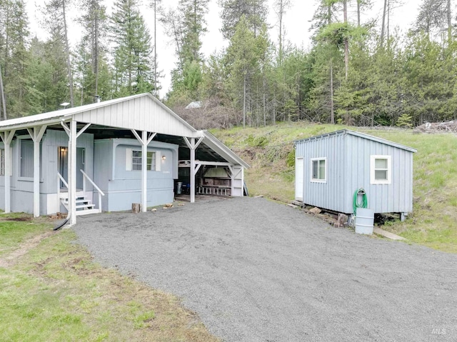 view of front of home featuring entry steps, a detached carport, and gravel driveway