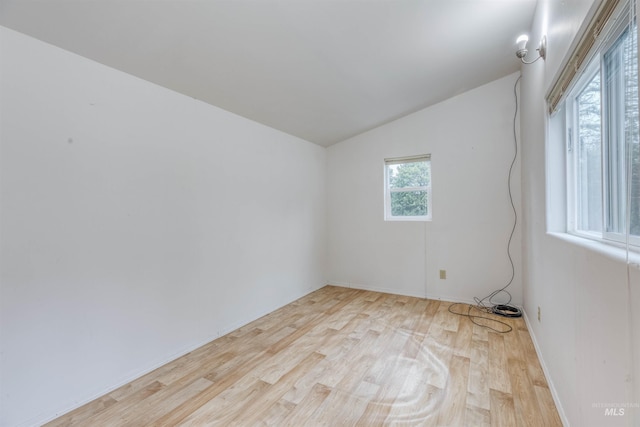 spare room featuring wood finished floors and vaulted ceiling