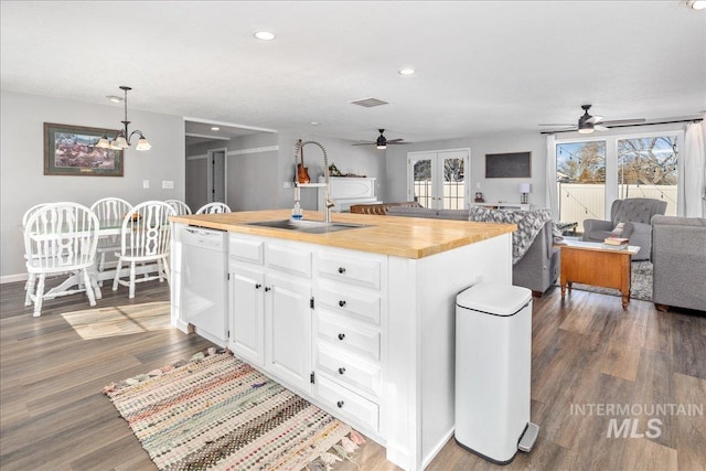 kitchen featuring white cabinetry, an island with sink, butcher block countertops, dishwasher, and open floor plan