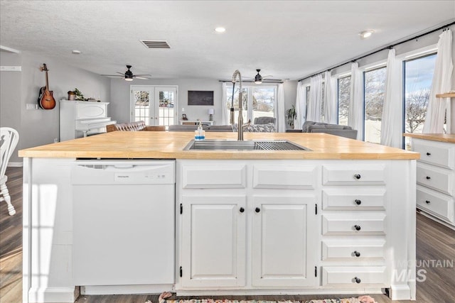 kitchen with wooden counters, open floor plan, white dishwasher, and white cabinets