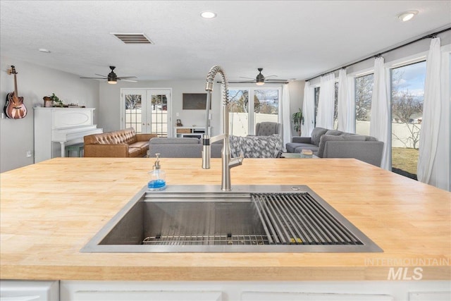 kitchen featuring visible vents, butcher block countertops, open floor plan, and a sink