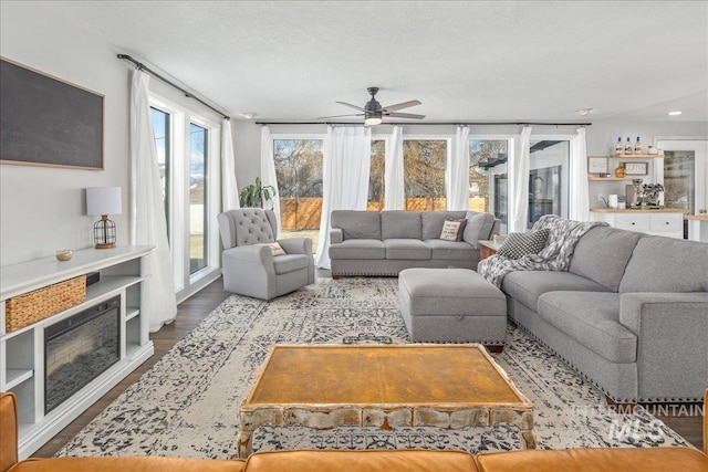 living area with a fireplace, wood finished floors, and a ceiling fan