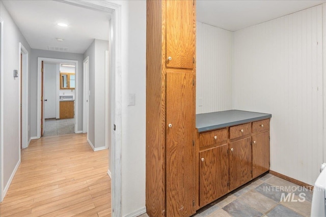 hall featuring light wood finished floors, visible vents, and baseboards