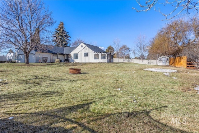 view of yard with a storage shed, fence, an outdoor structure, and an outdoor fire pit