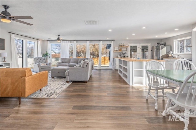 living room with dark wood-type flooring, recessed lighting, visible vents, and a textured ceiling