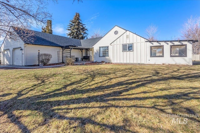 back of house featuring an attached garage, a lawn, and board and batten siding