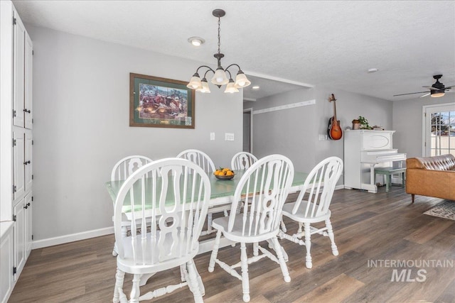 dining area with dark wood finished floors, ceiling fan with notable chandelier, a textured ceiling, and baseboards