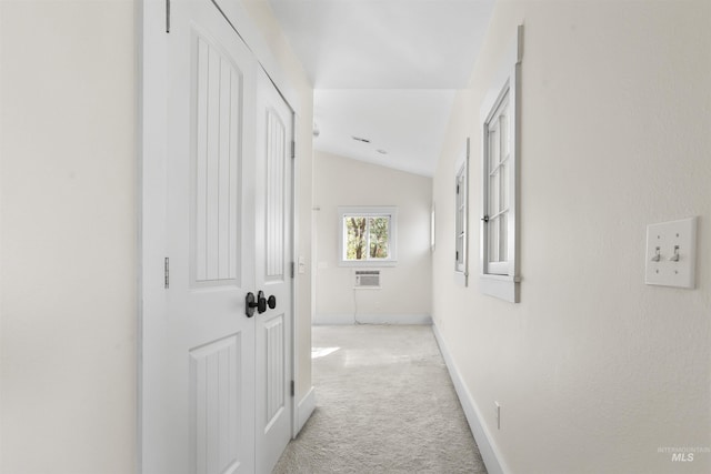 corridor featuring lofted ceiling, a wall mounted AC, and light colored carpet