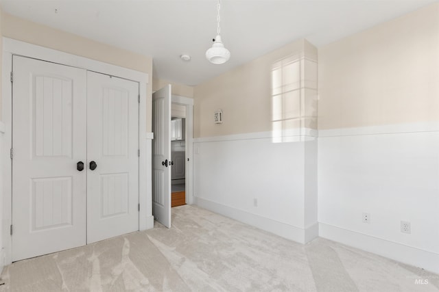 unfurnished bedroom with a closet and light colored carpet