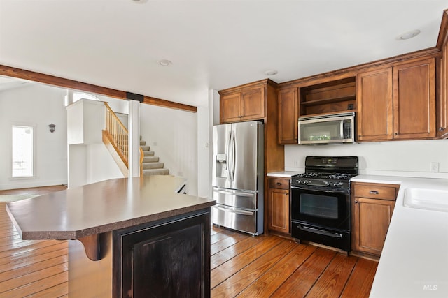 kitchen with a breakfast bar area, stainless steel appliances, and dark hardwood / wood-style flooring