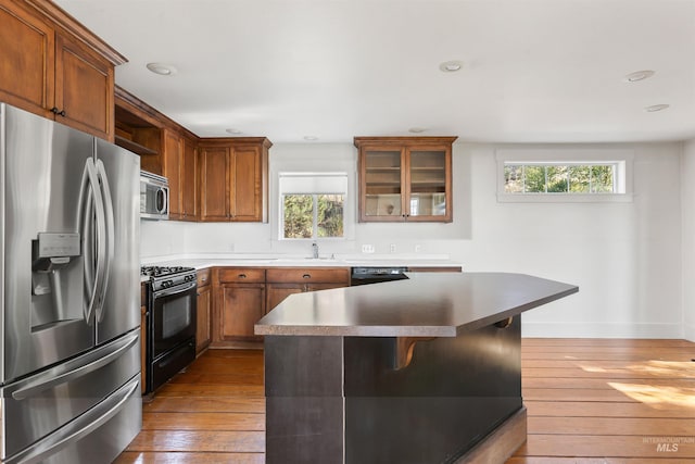 kitchen with wood-type flooring, black appliances, a wealth of natural light, and a kitchen breakfast bar