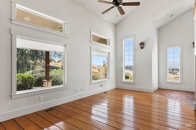 empty room with ceiling fan, hardwood / wood-style flooring, and high vaulted ceiling