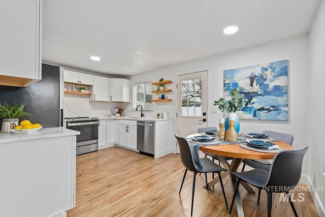 916 N 32nd St, Boise, ID 83702 - kitchen with light wood-type flooring, open shelves, white cabinets, appliances with stainless steel finishes, and light countertops