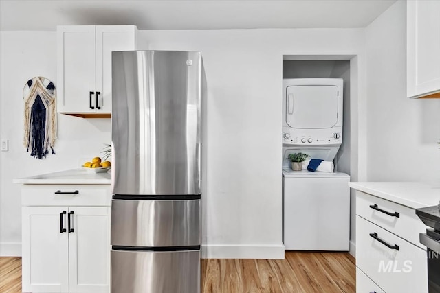 916 N 32nd St, Boise, ID 83702 - kitchen featuring white cabinets, light countertops, light wood-type flooring, freestanding refrigerator, and stacked washer and dryer