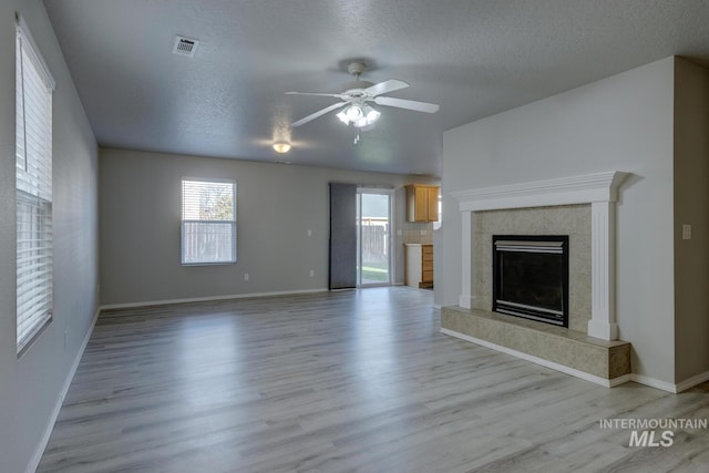 unfurnished living room with ceiling fan, a textured ceiling, and light wood-type flooring