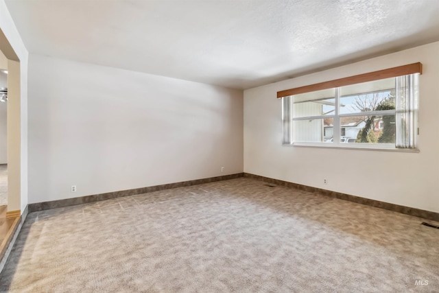 carpeted empty room with baseboards and a textured ceiling