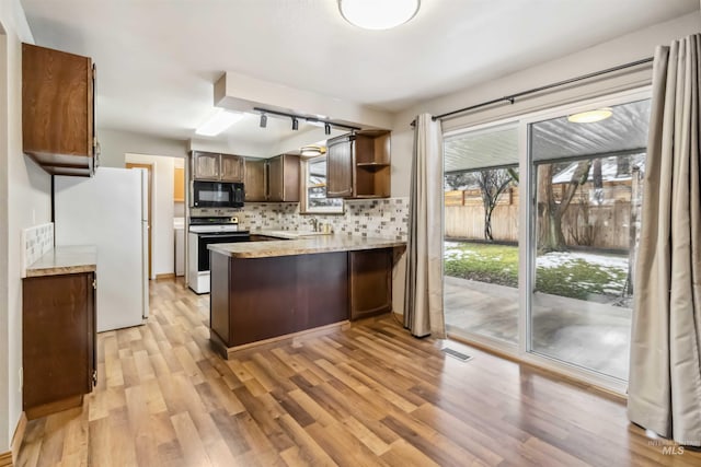 kitchen featuring visible vents, a peninsula, freestanding refrigerator, range with electric cooktop, and black microwave