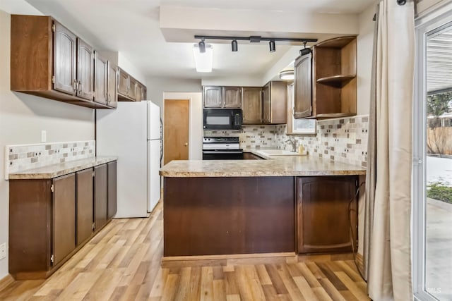 kitchen featuring electric range, a sink, freestanding refrigerator, black microwave, and light countertops