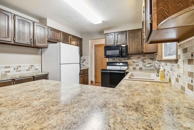 kitchen featuring a sink, electric range oven, freestanding refrigerator, black microwave, and decorative backsplash