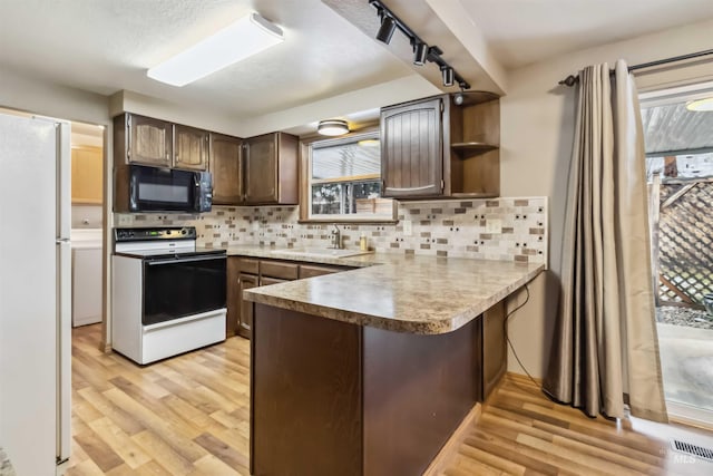 kitchen with a sink, electric range oven, freestanding refrigerator, a peninsula, and black microwave