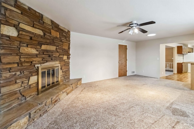 unfurnished living room with a ceiling fan, light colored carpet, and a fireplace