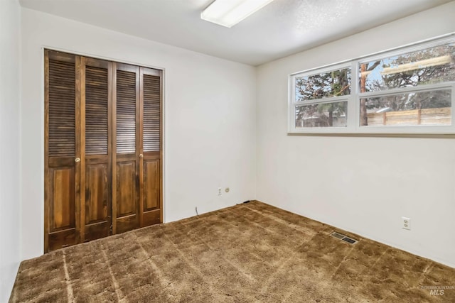 unfurnished bedroom with visible vents, carpet floors, multiple windows, and a closet