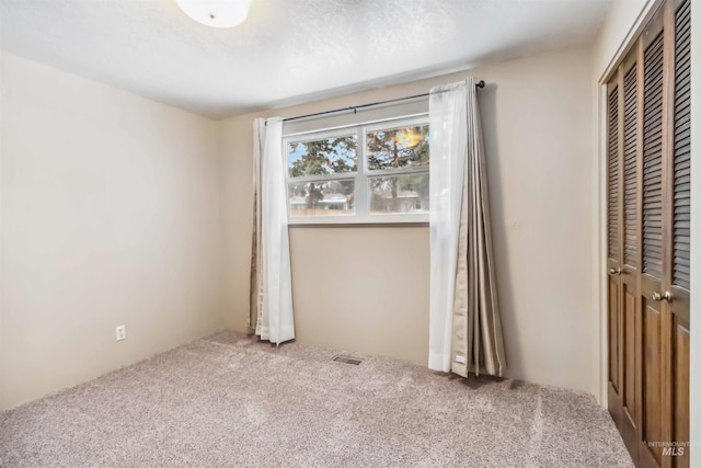 unfurnished bedroom with a closet, carpet floors, a textured ceiling, and visible vents