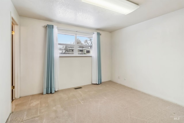 spare room featuring visible vents, carpet floors, and a textured ceiling