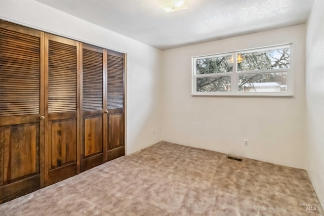 unfurnished bedroom with visible vents, a closet, and carpet flooring