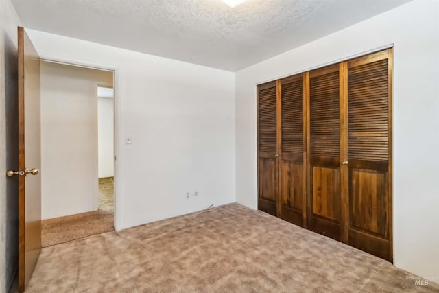 unfurnished bedroom featuring a closet, carpet floors, and a textured ceiling