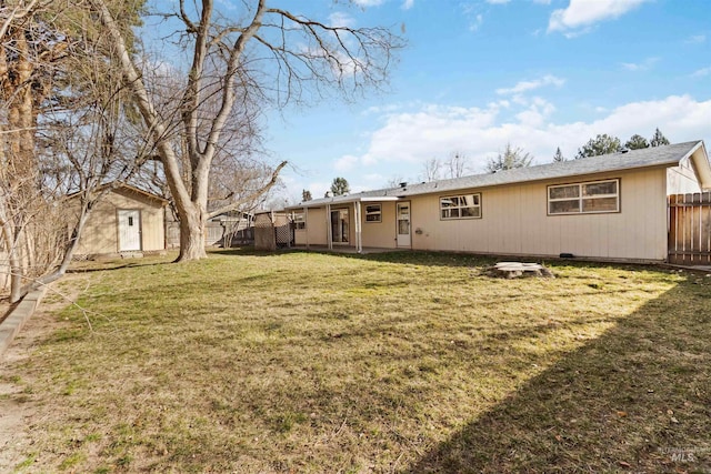 back of property featuring a lawn, an outdoor structure, and fence