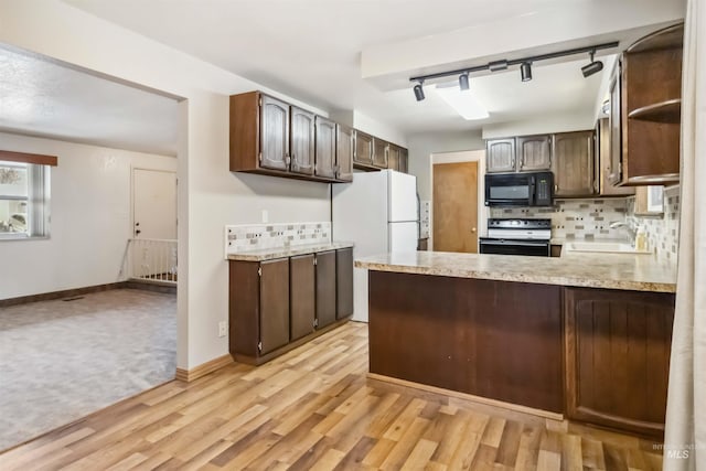 kitchen featuring a sink, range with electric cooktop, light countertops, black microwave, and tasteful backsplash